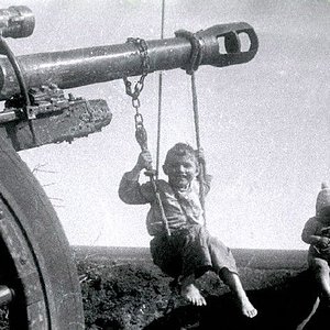 Russian boy swings on Nazi cannon which is left by German troops in Soviet